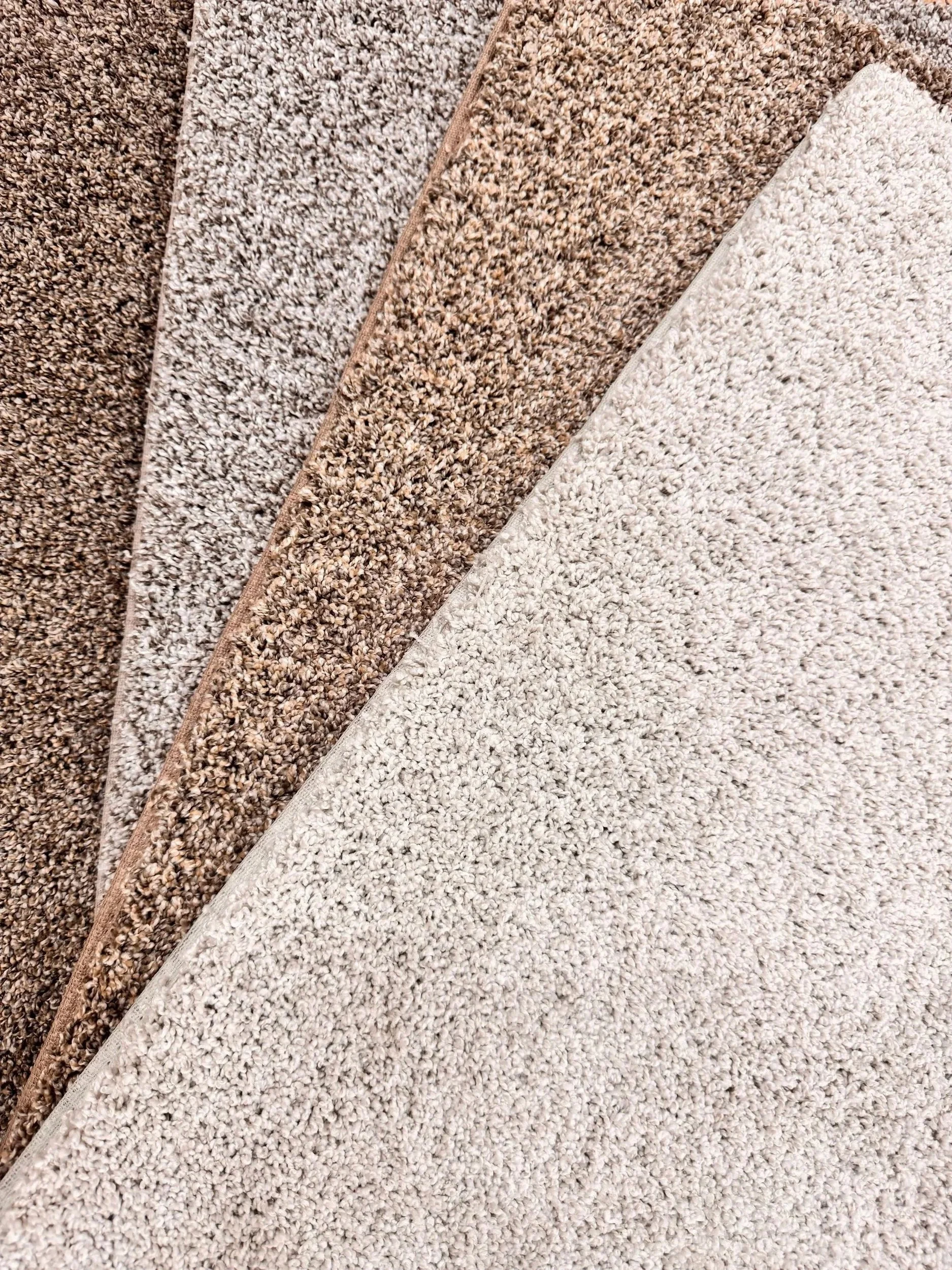Four different colored carpet samples laid out flat, ranging from dark brown to light beige.