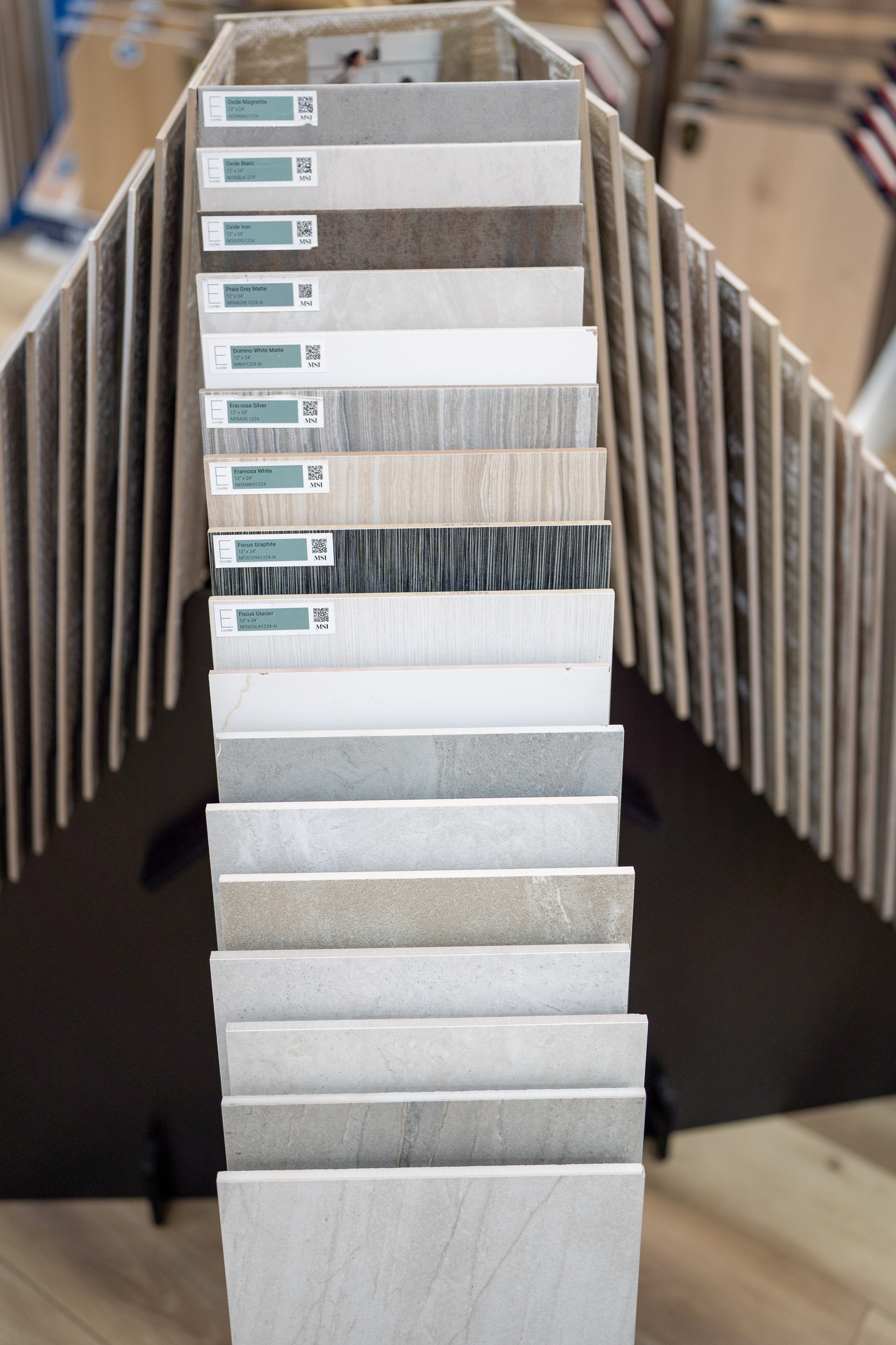 Display stand with various tile samples in neutral colors and different textures at Seamless Floors showroom located in St Augustine.