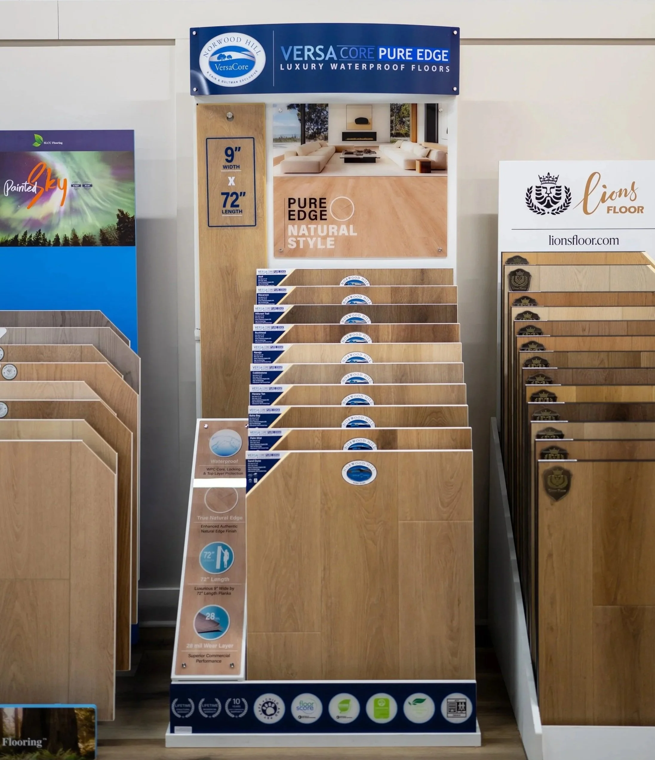 Display stand showcasing VersaCore Pure Edge Natural Style waterproof flooring in various shades of wood finishes, with product information and features highlighted.