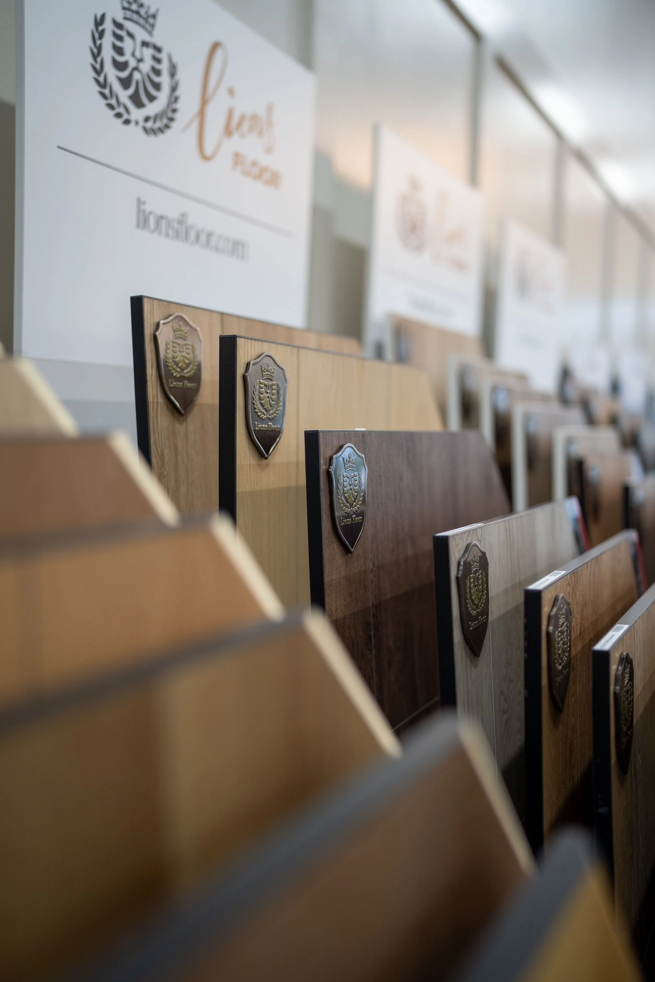 Display of various laminate flooring samples with a sign in the background for a flooring company.