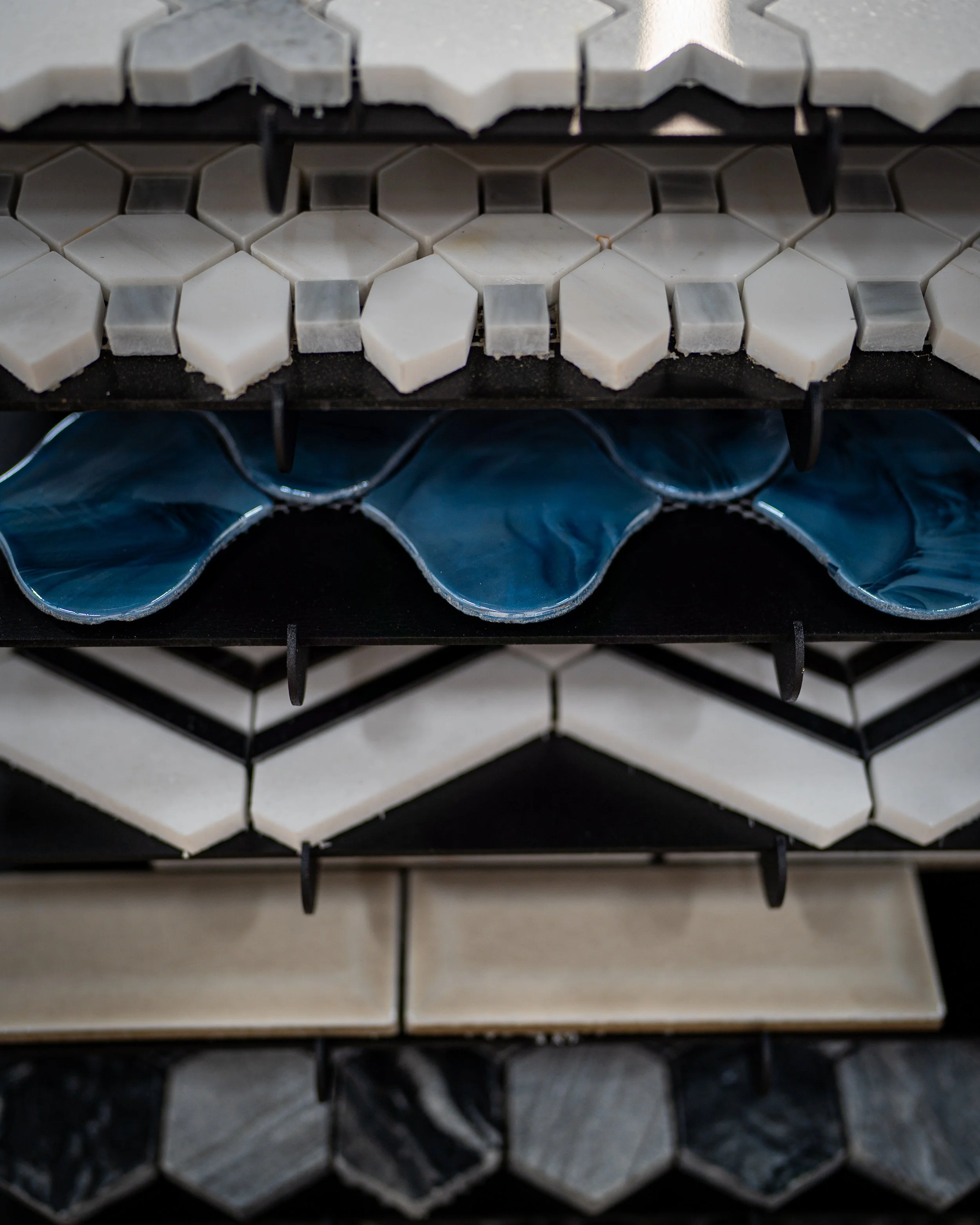 Close-up view of various tiles of different shapes, sizes, and colors on display shelves.