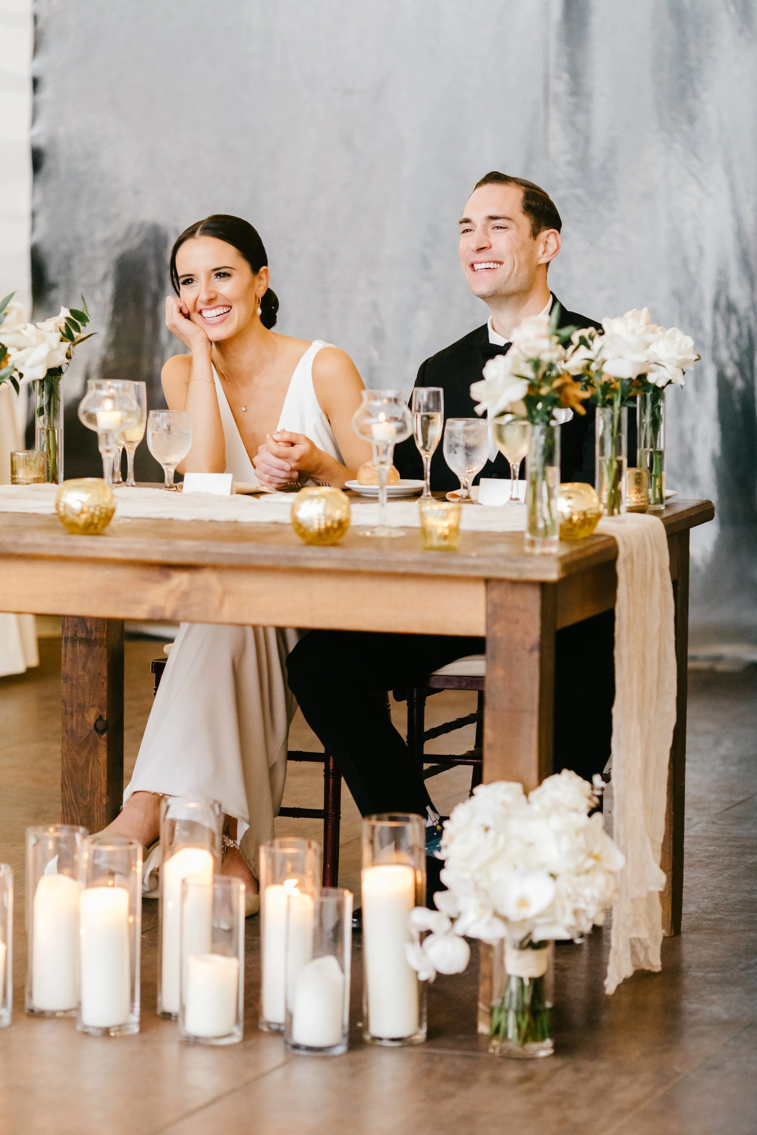 A bride and groom seated at a table smiling