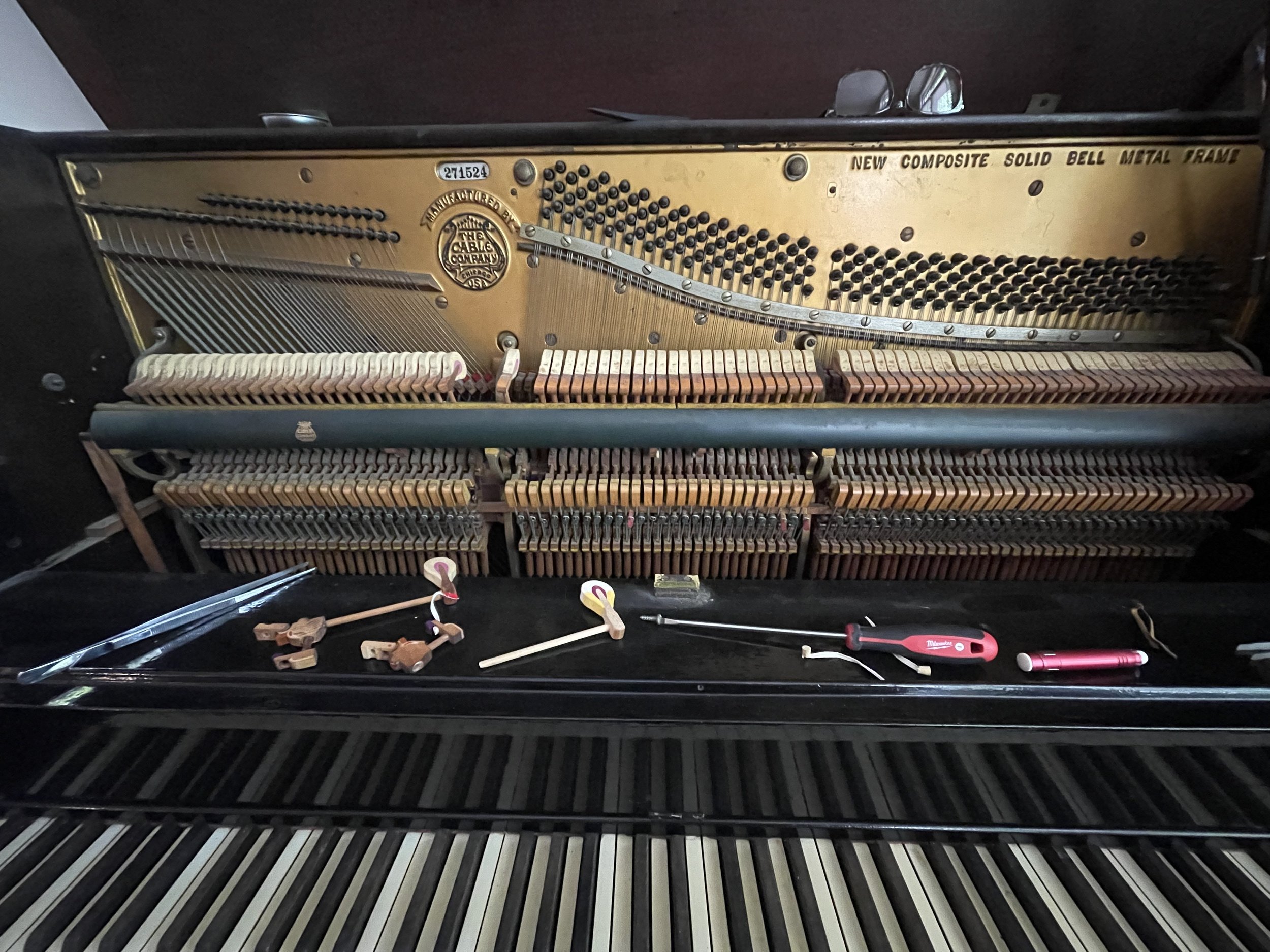 A vintage grand piano action being pulled out of the piano by a piano technician.