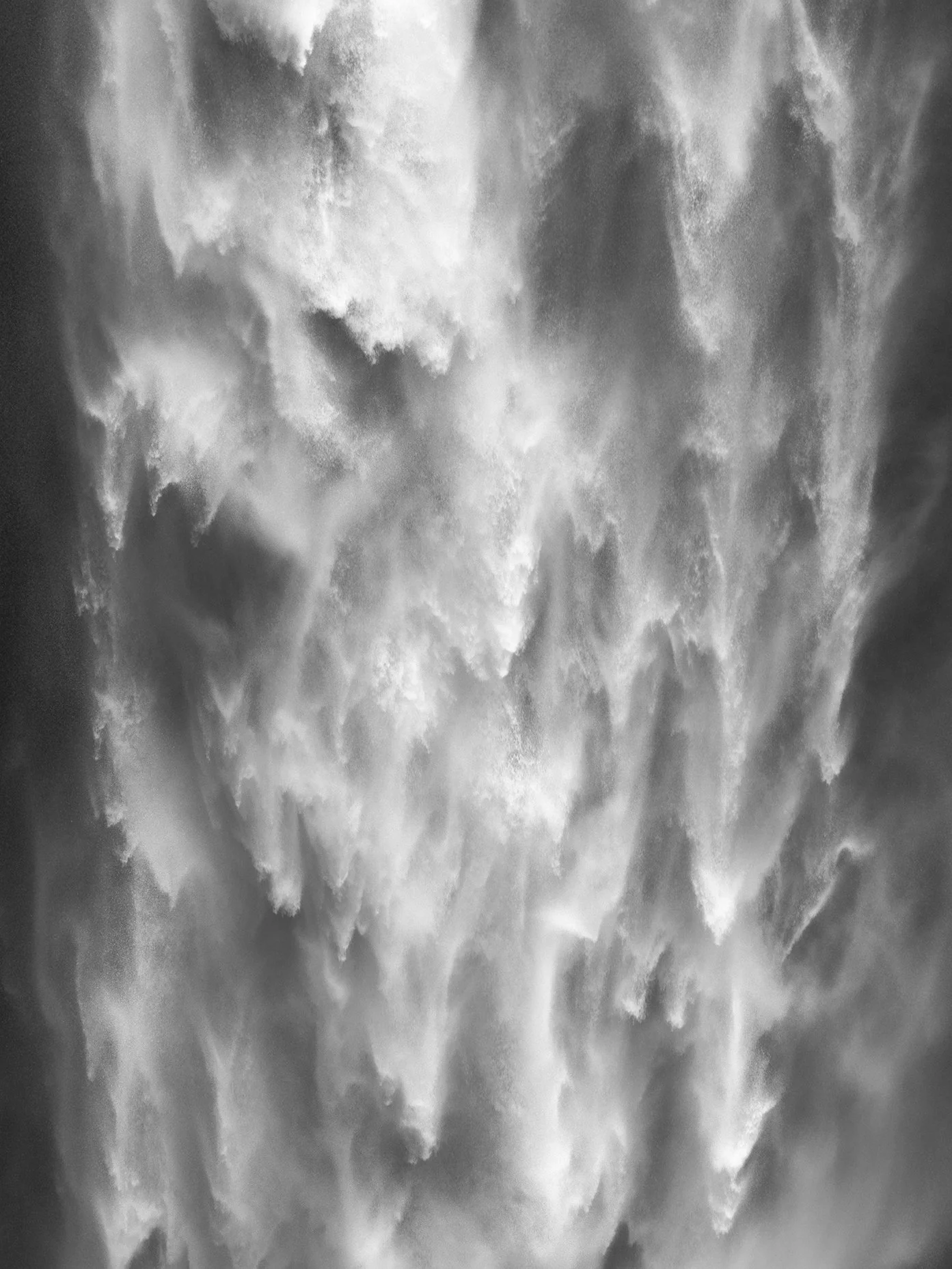 Black and white photograph of cascading water in a waterfall, creating mist and spray.