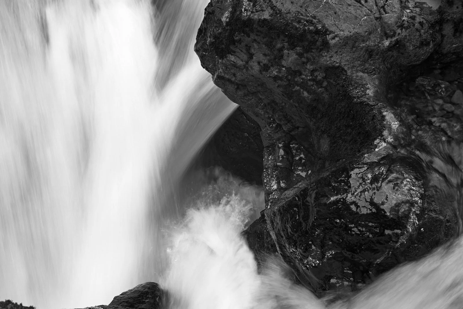 Black and white photo of water rushing over rocks in a river or stream.