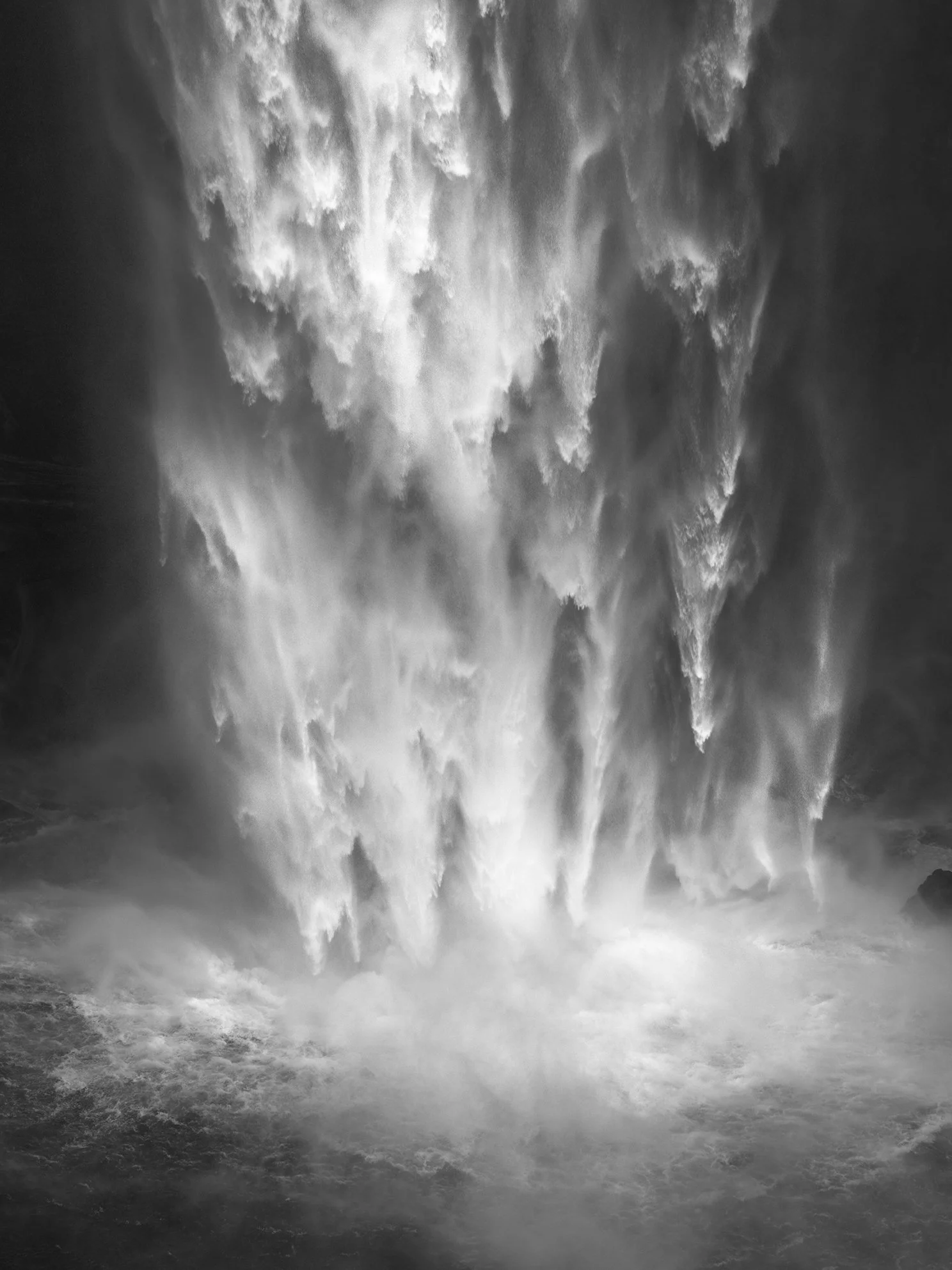 Black and white image of a powerful waterfall with water cascading down from high above.
