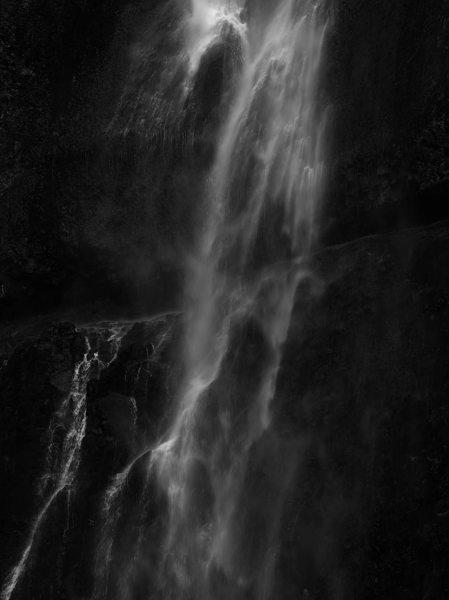 A black and white photograph of water cascading down a rocky cliff, resembling a waterfall.