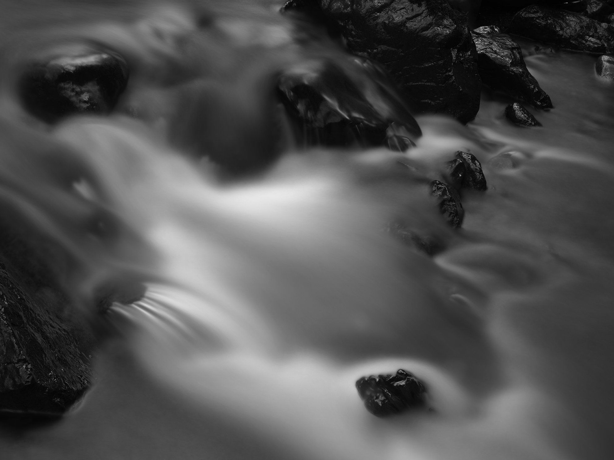 Black and white photo of water flowing over rocks in a stream.