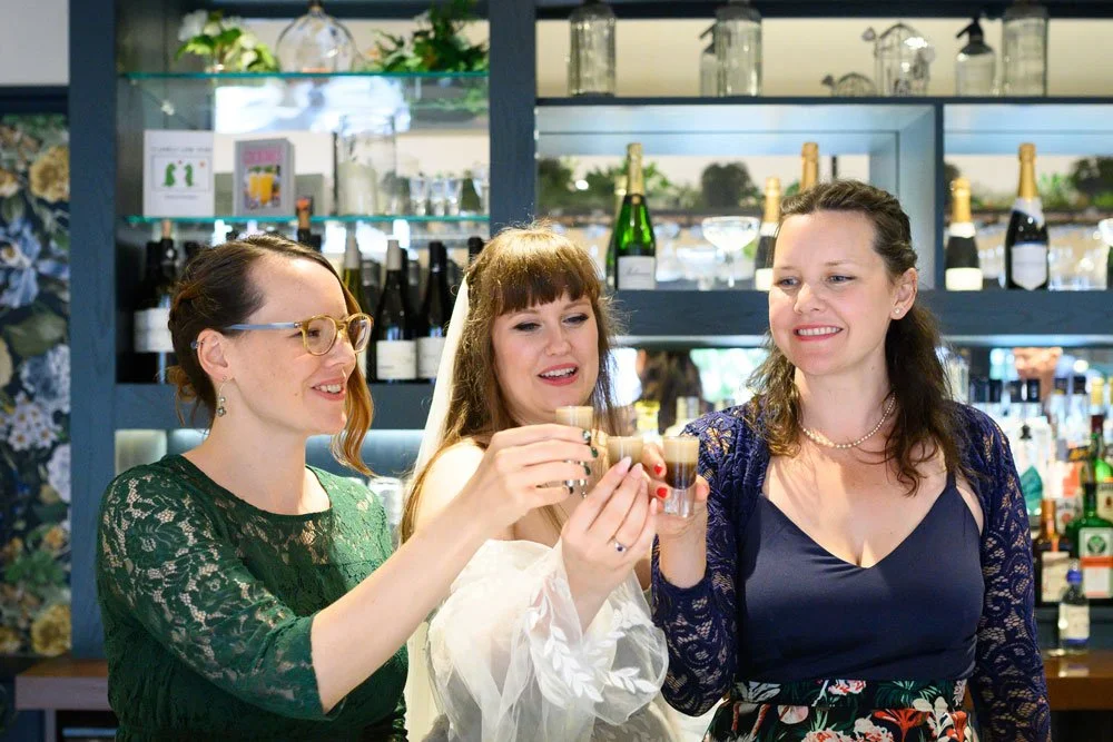 bride and two sisters in bar holding shots of guinness