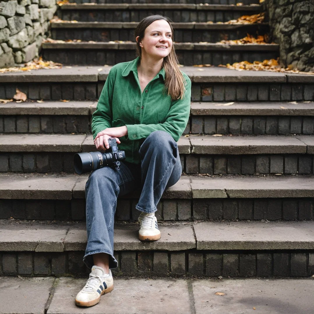 lady sitting on stairs holding a camera in one hand