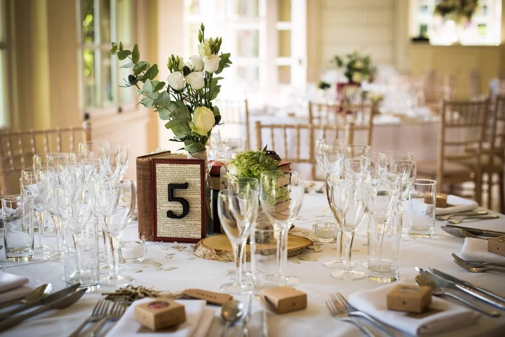 A table decorated for a wedding breakfast with a book and flowers in the centre