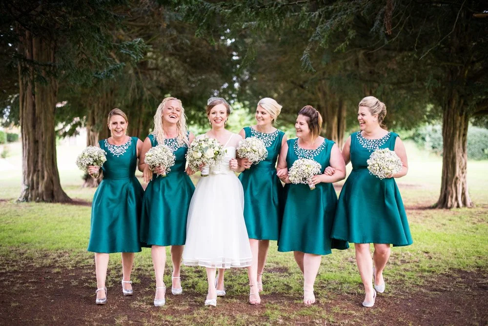 Bride and bridesmaids walking and laughing whilst holding bouquets