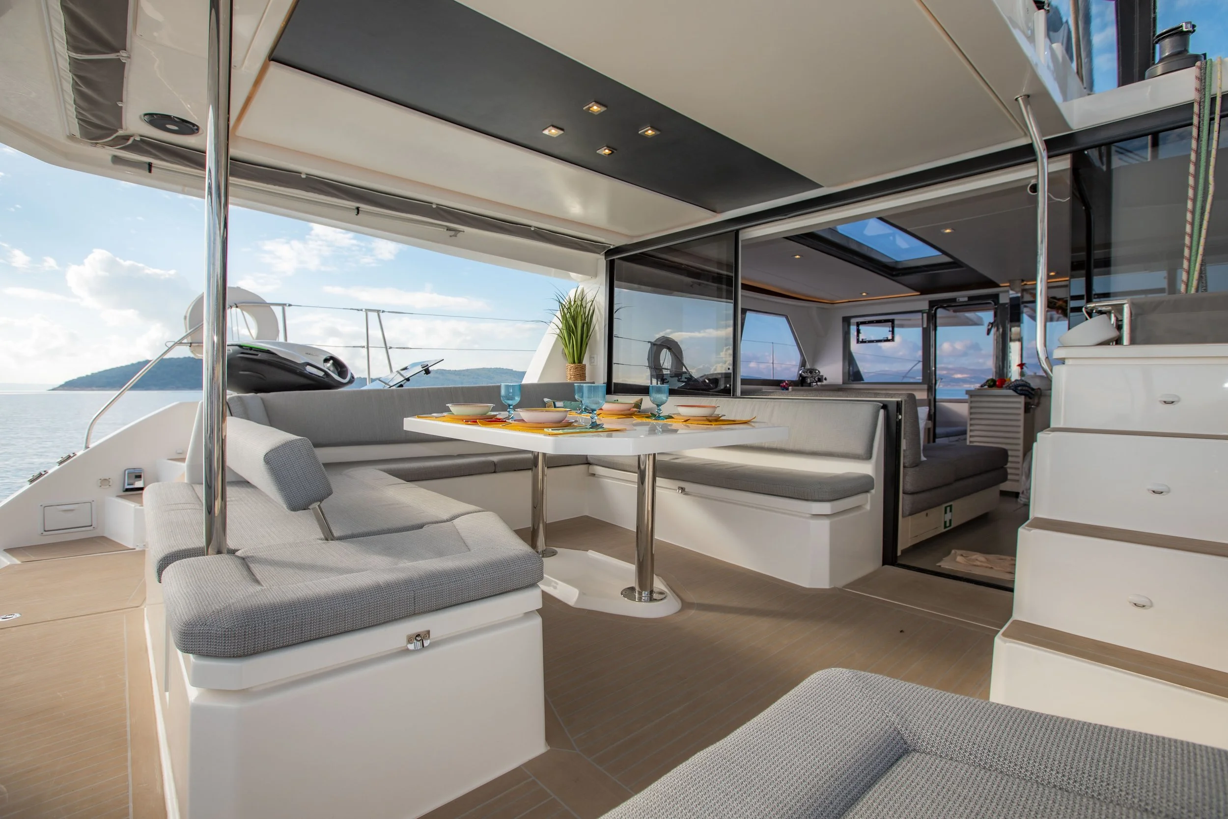 Interior of a luxury yacht with a dining area and seating, open to views of the ocean and sky.