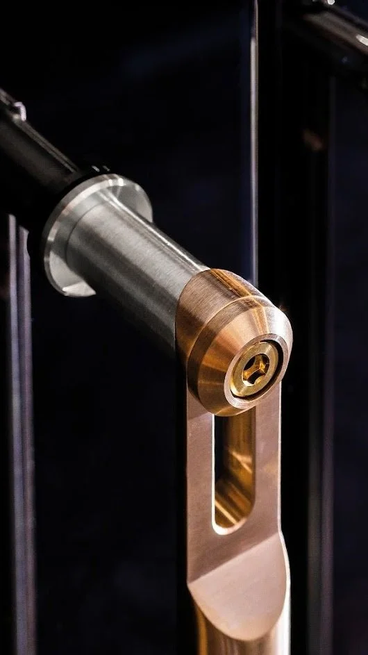 Close-up of a modern, metallic door handle with a cylindrical design, mounted on a black door.