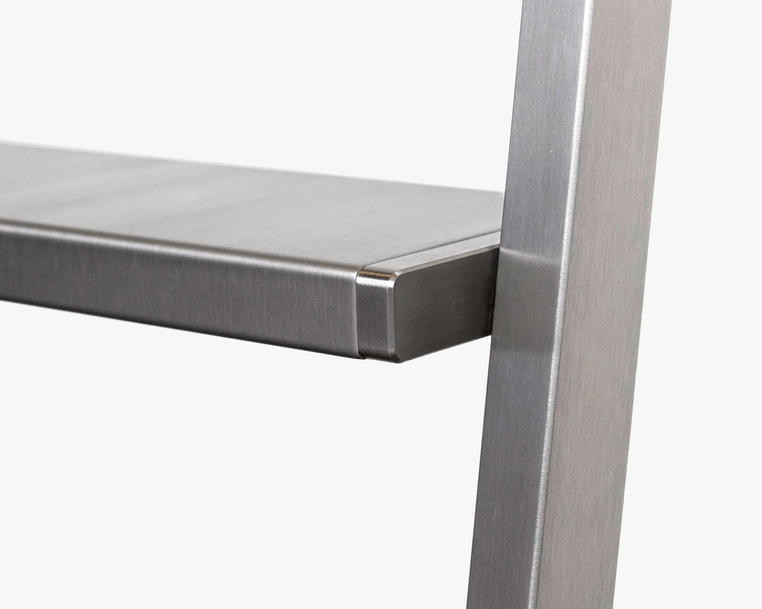 Close-up of a metallic object with a flat surface and a vertical support, showing detailed brushed metal texture.