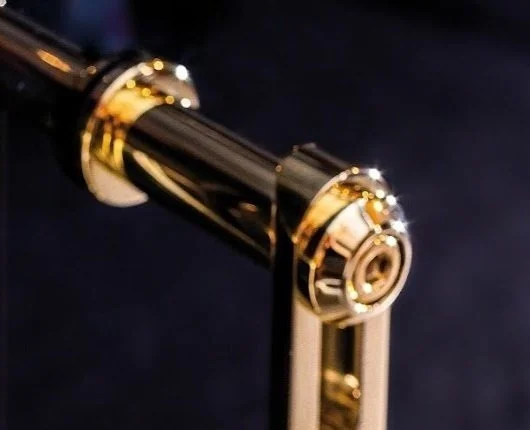 Close-up of a gold and black faucet handle against a dark background.