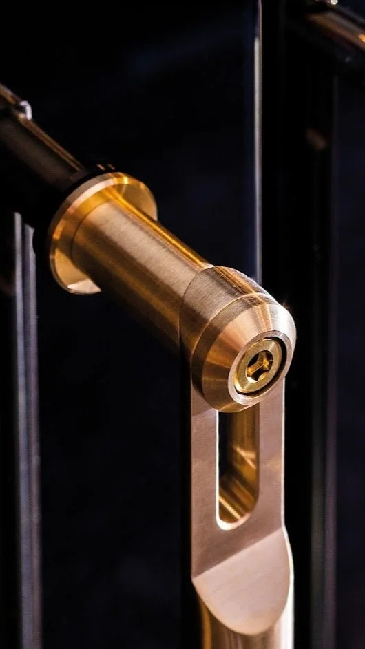 Close-up of a modern gold-colored door handle and lock on a dark door.