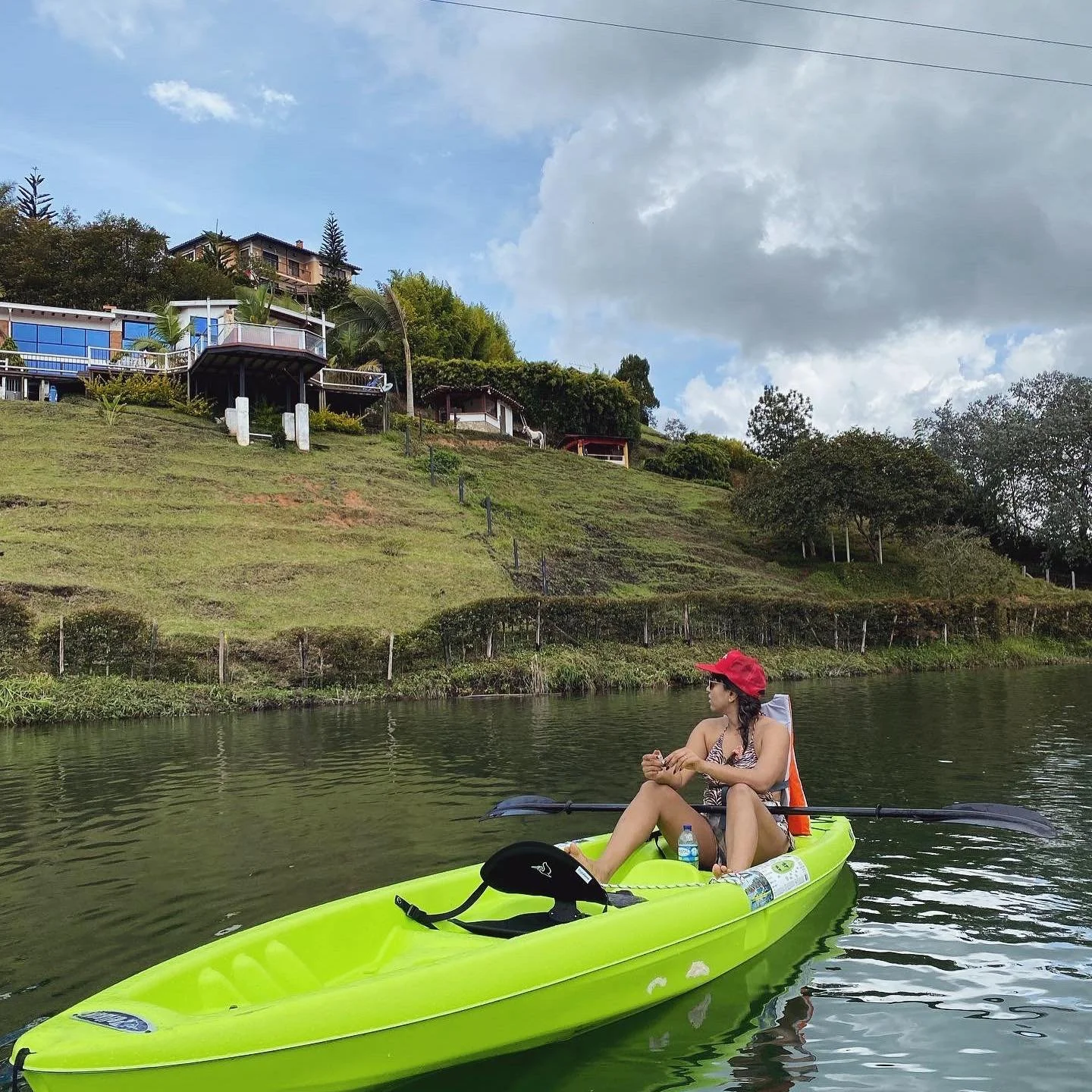Person kayaking on a lake with houses on a hillside in the background.