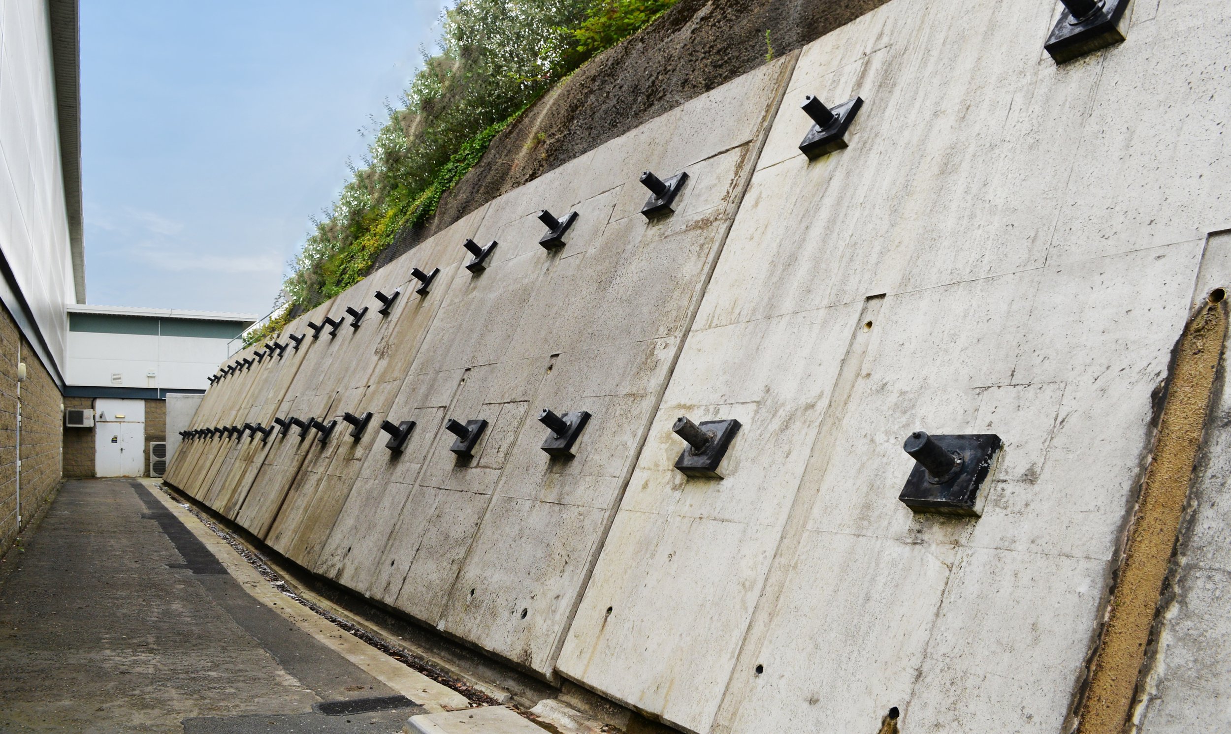 Concrete retaining wall with anchors, pathway, and building