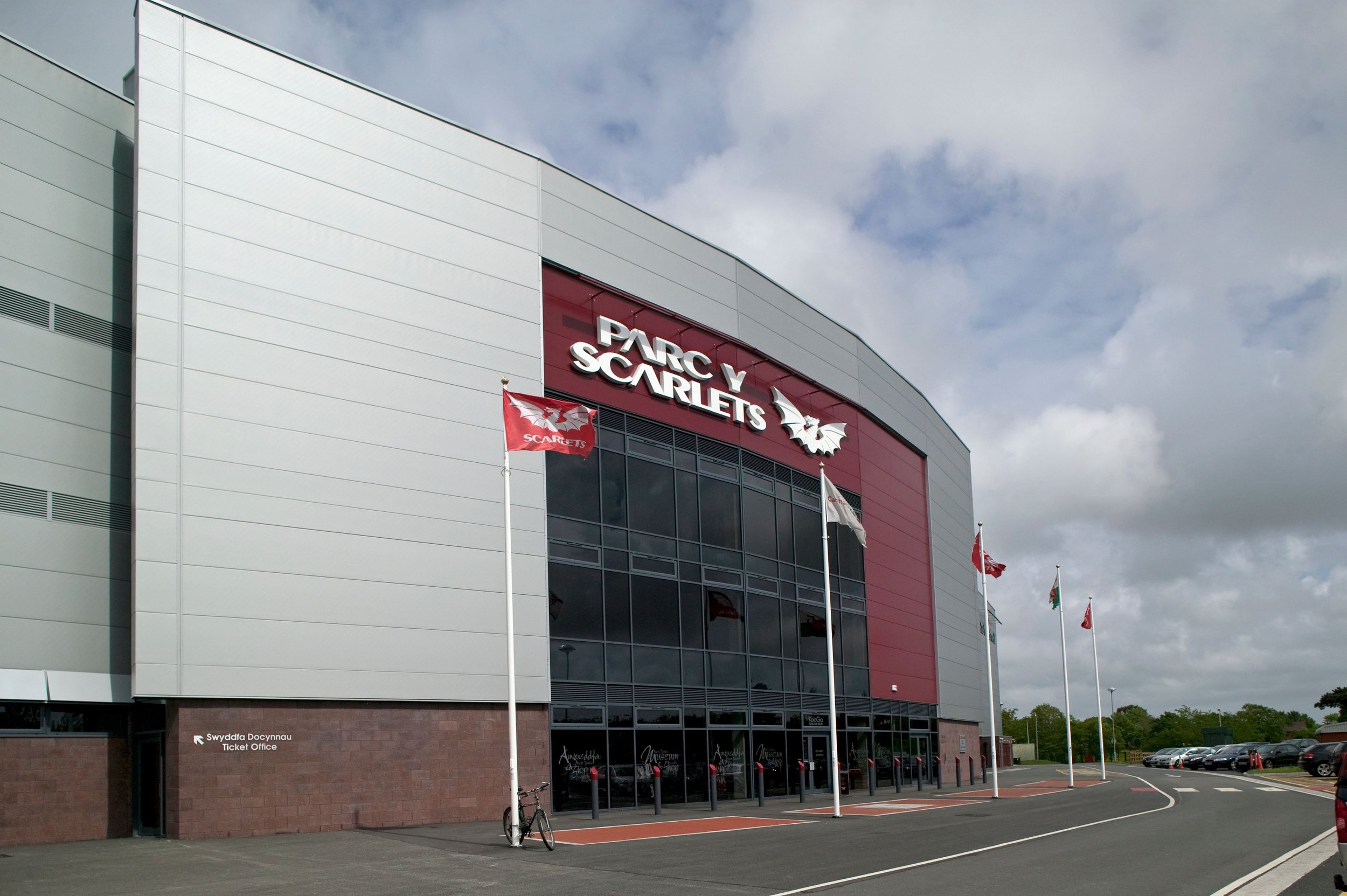 Exterior of Parc y Scarlets stadium with flags and a ticket office.