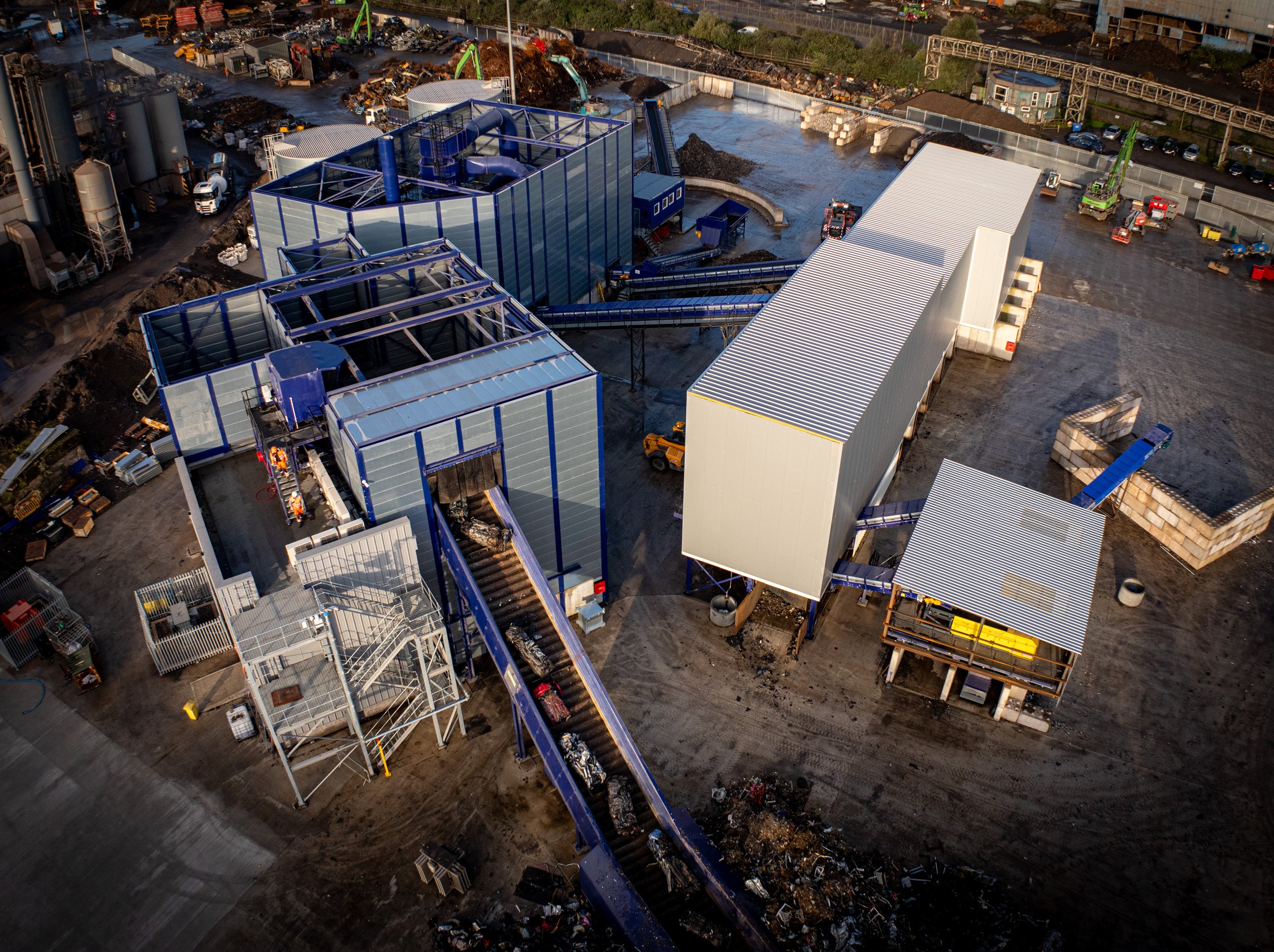Industrial recycling plant with large metal structures, conveyer belts, and machinery for sorting waste materials.