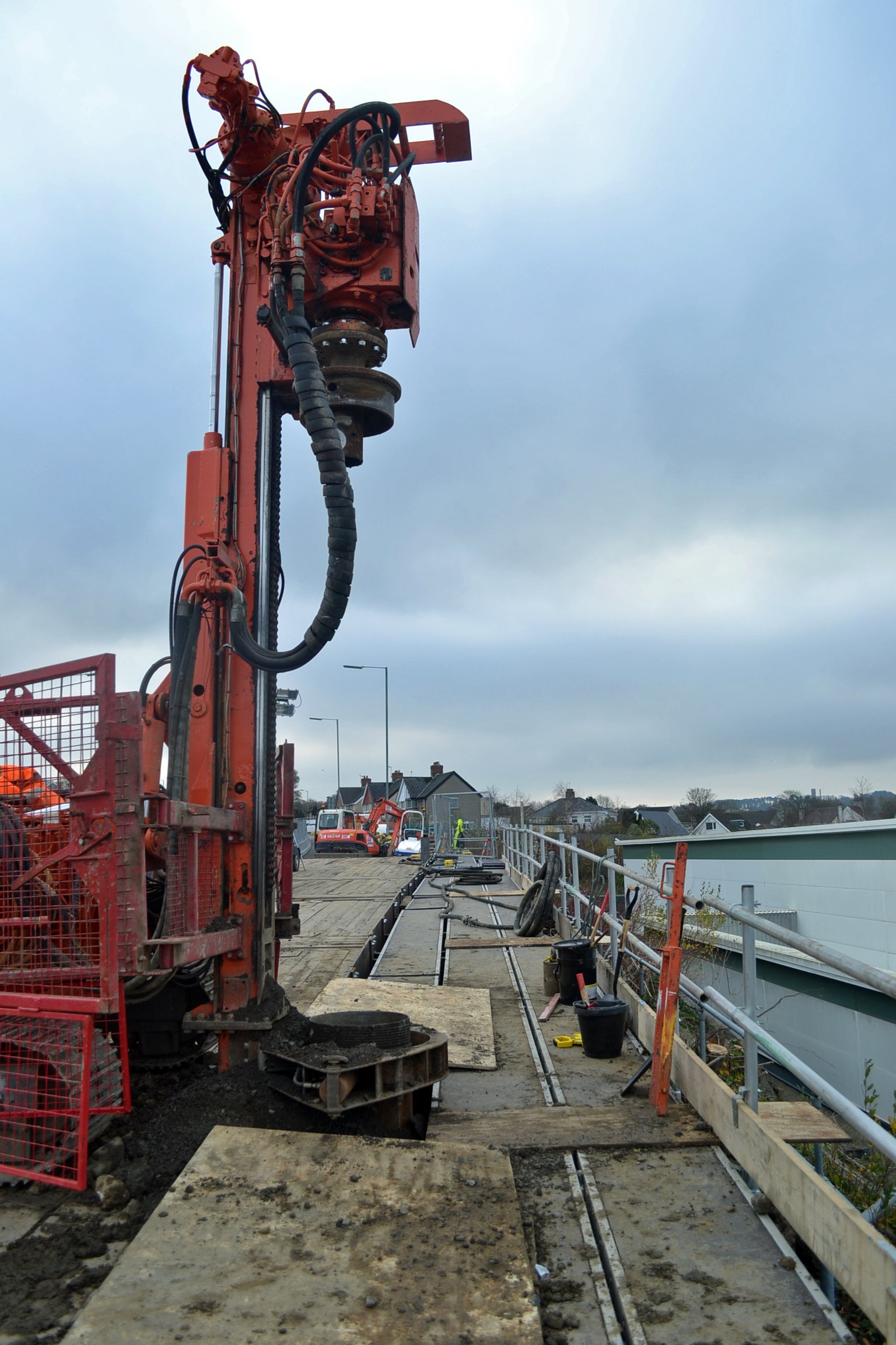 Construction site with drilling machine on a bridge with wooden planks and equipment.
