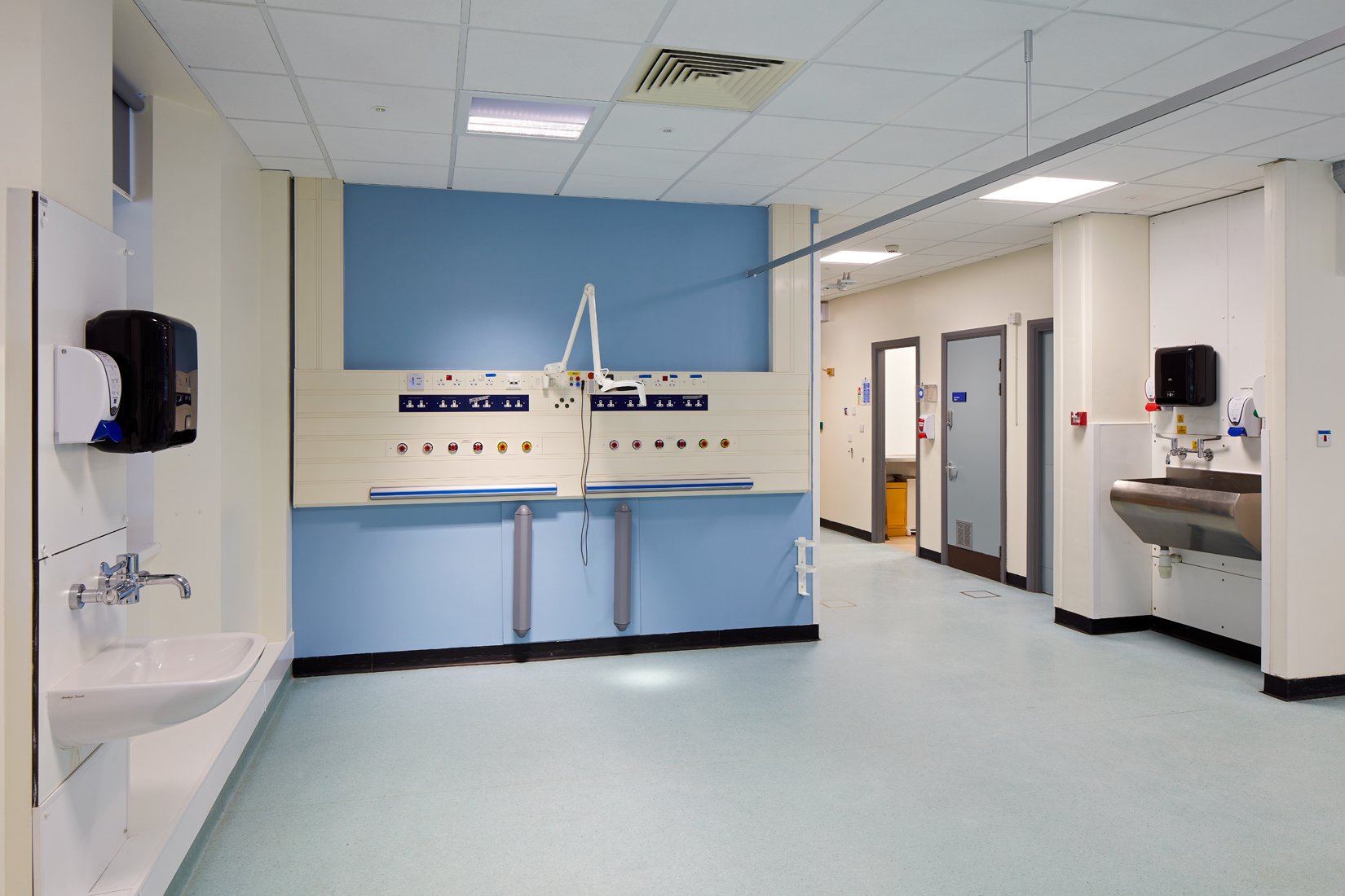 Hospital room with medical equipment, sink, and corridor with doors.