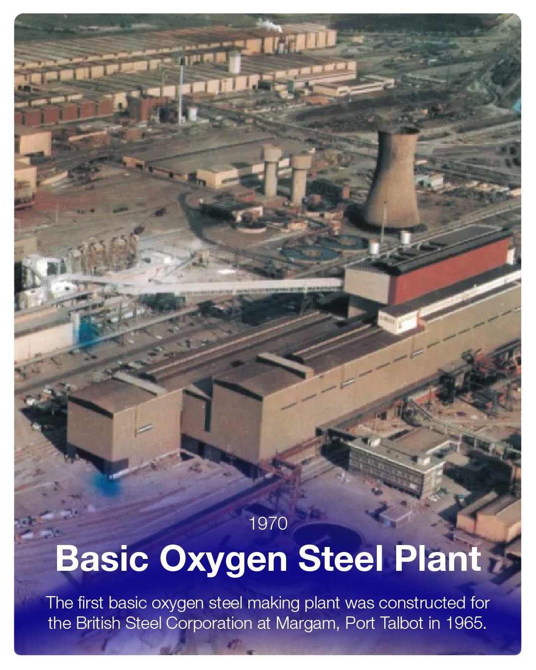 Aerial view of a 1970s oxygen steel plant with large cooling tower, industrial buildings, and smoke stacks, located at Margam, Port Talbot.