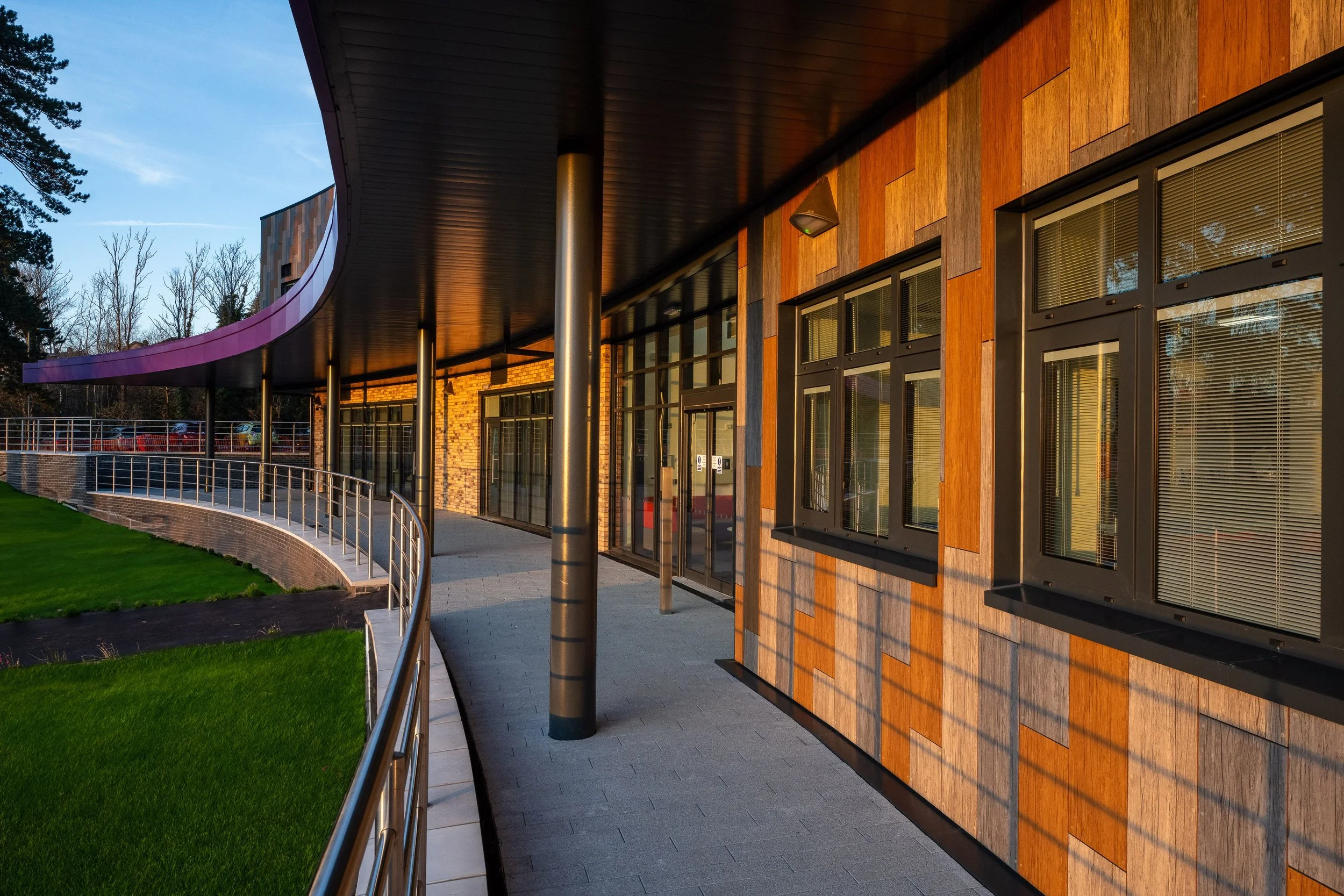Modern building exterior with curved walkway and wooden paneling