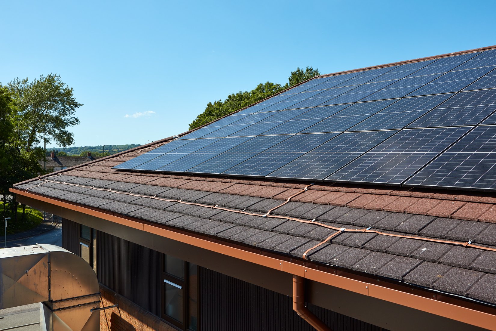 Solar panels installed on a sloped residential roof on a sunny day.