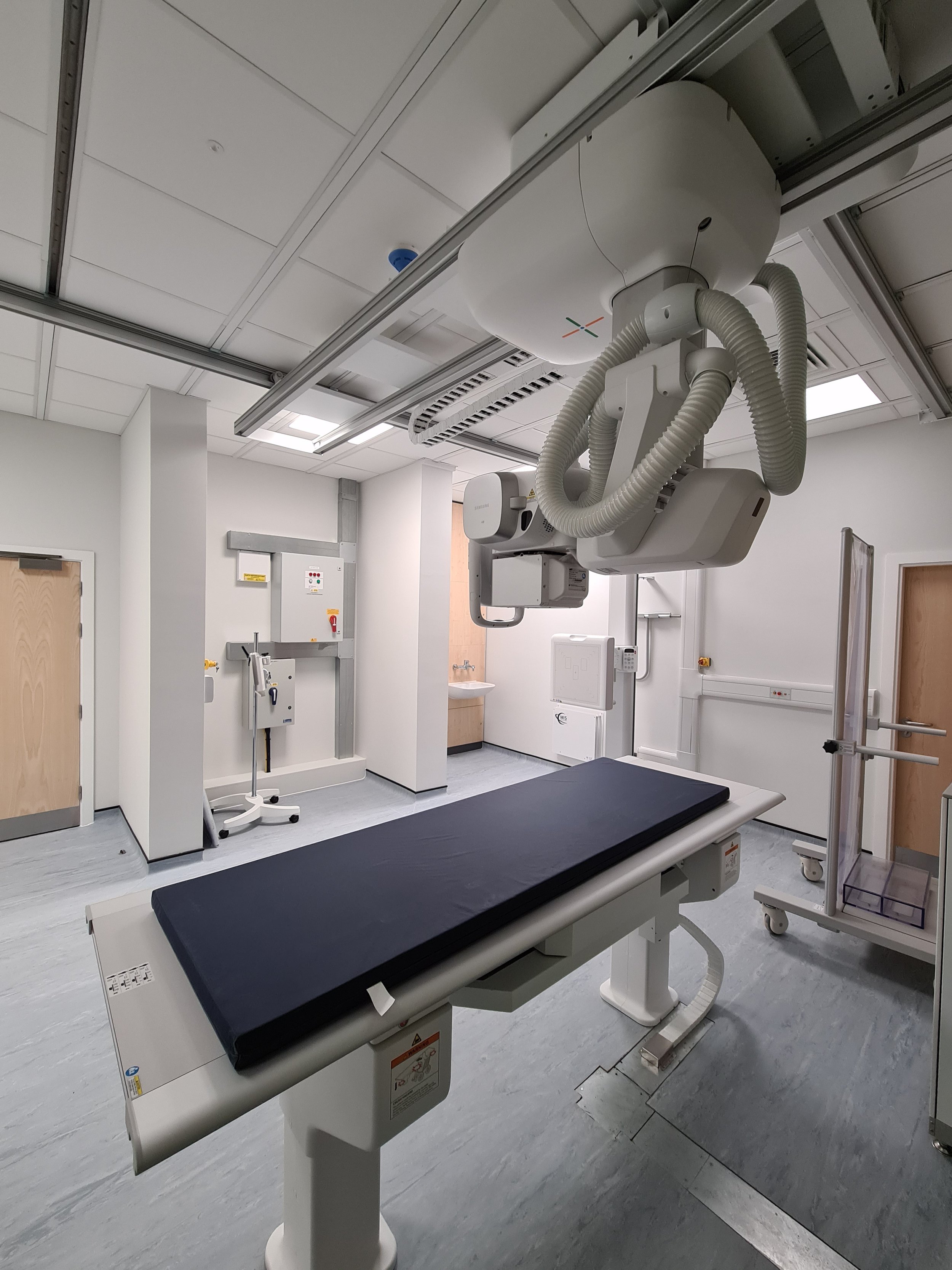 Hospital X-ray room with machinery and examination table