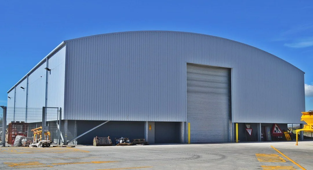 Large industrial warehouse with closed rolling doors and outdoor equipment.