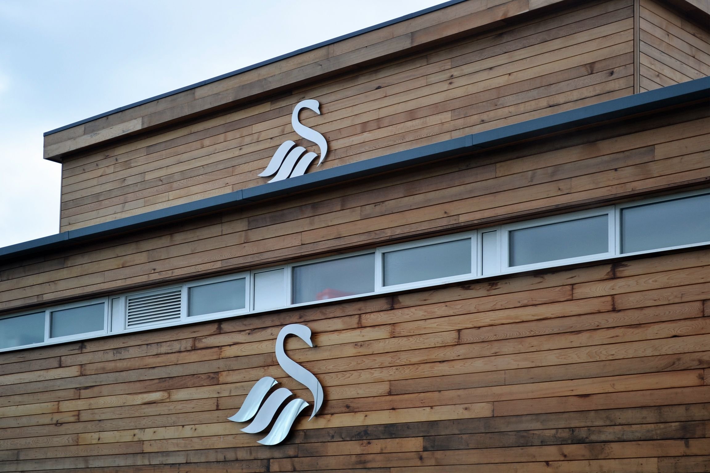 Wooden building with swan logos and small windows
