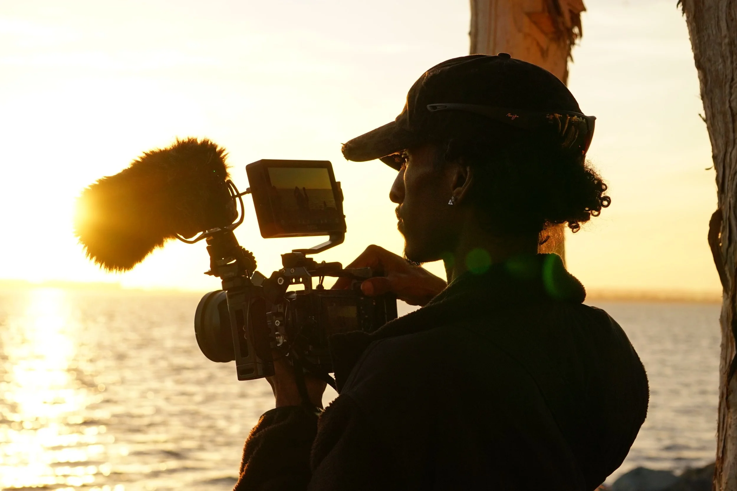 A photo of Nico Yeager during sunset, holding a film camera recording BTS for a short film.