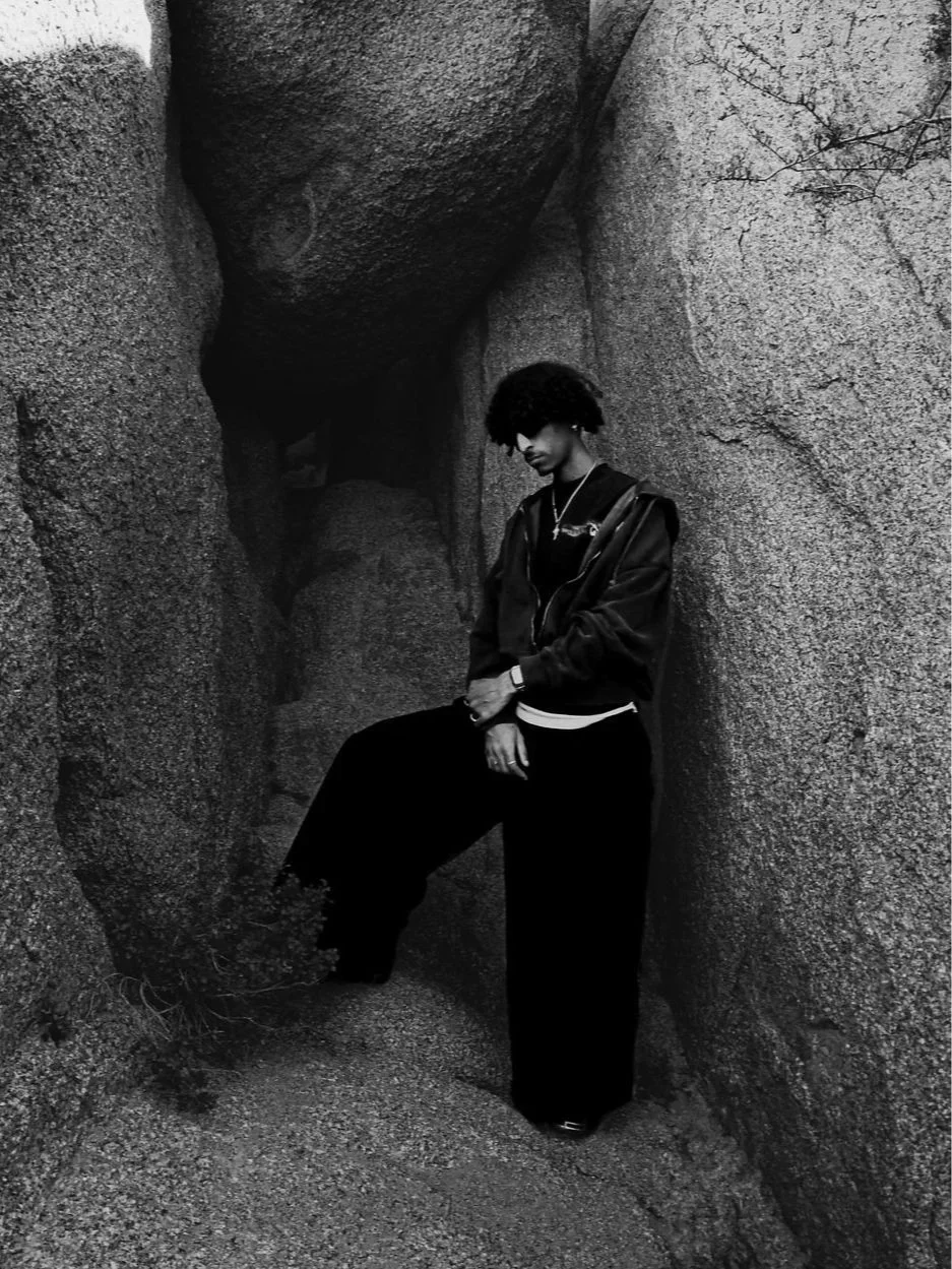 A picture of Nico Yeager, leaning up against the rock and Joshua Tree, modeling himself for his website where he promotes his photography and videography business.