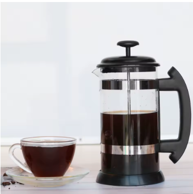 French press with brewed coffee and a coffee cup on a saucer.