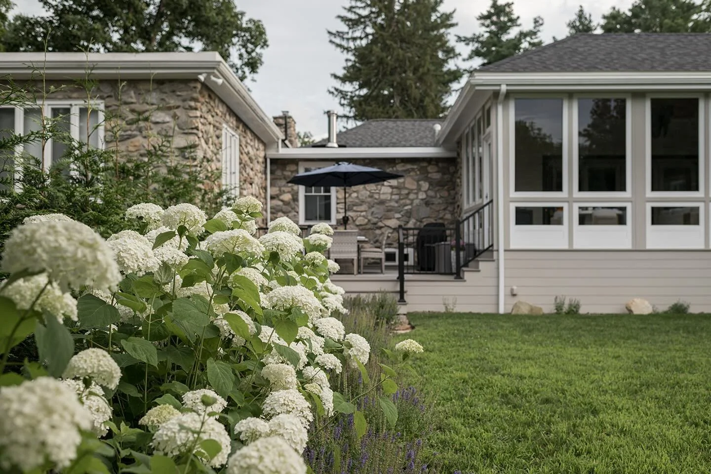 There is something timeless about a stone home framed by lush white hydrangeas. This backyard is a quiet retreat, a place to gather, unwind, and soak in the beauty of intentional design. Imagine spending a spring, summer or fall evening here, surroun