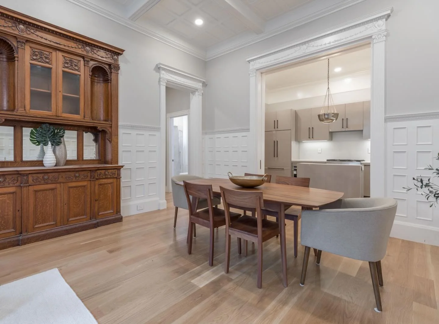 Where history holds its ground and modern living steps in with intention.

In this dining room, intricate millwork, coffered ceilings, and original detailing set a richly layered foundation. Just beyond, the kitchen shifts the narrative. Streamlined 