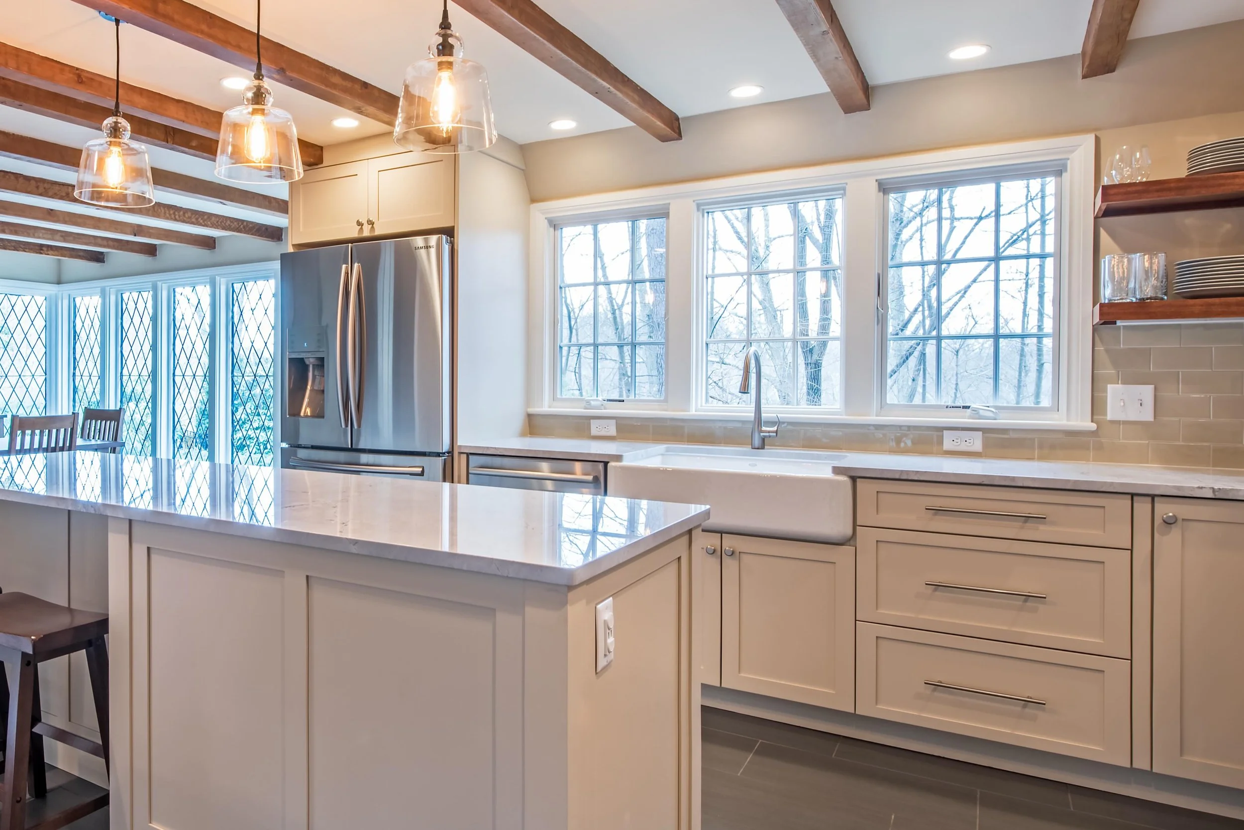Where craftsmanship meets quiet luxury.

This kitchen was designed to feel as effortless as it is elevated. Warm wood ceiling beams draw your eye upward, while soft neutral cabinetry and layered textures create a sense of calm, balance, and intention