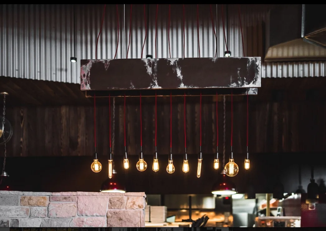 Industrial-style pendant light fixture with exposed bulbs hanging from red cords.