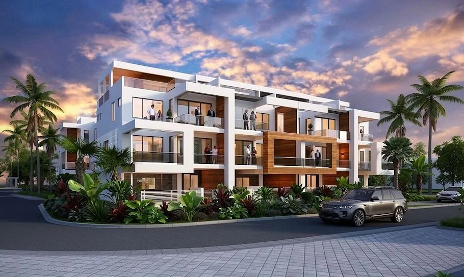 Modern multi-story residential building with balconies, surrounded by palm trees and tropical plants, at sunset.