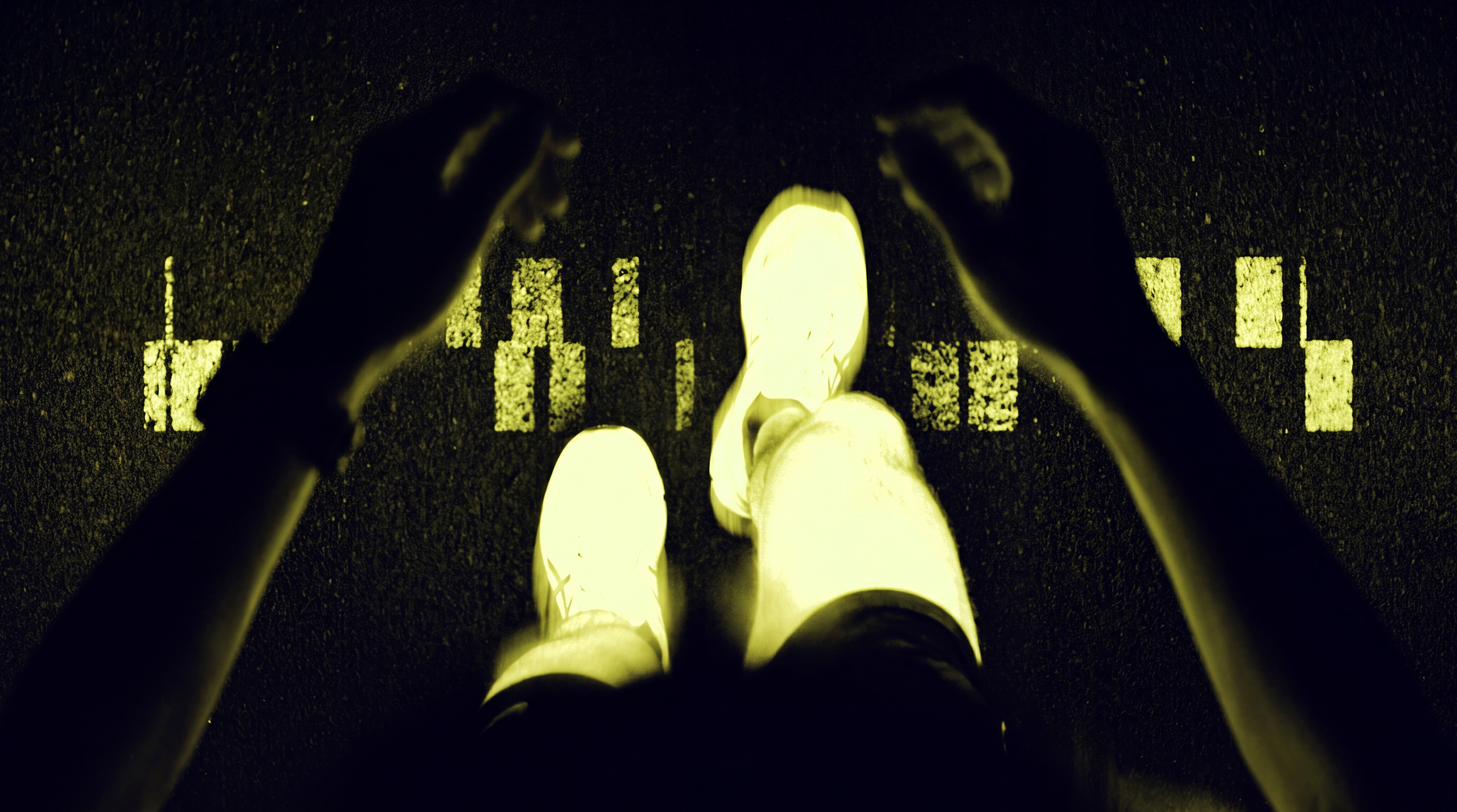 A person standing on a dark road at night, wearing white shoes and white pants, with their hands adjusting their hair or hat.
