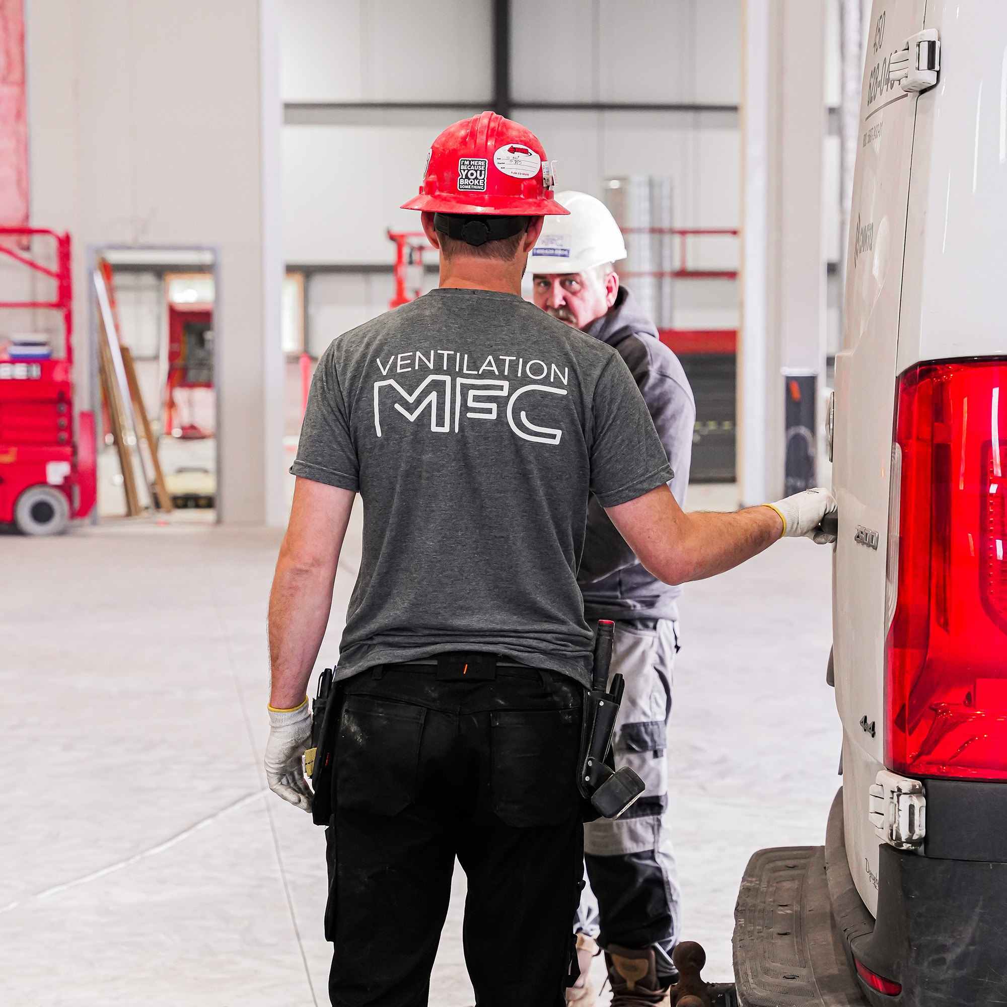 Deux ouvriers en casque de sécurité discutent près d’un camion dans une zone de construction ou d’aménagement intérieur.
