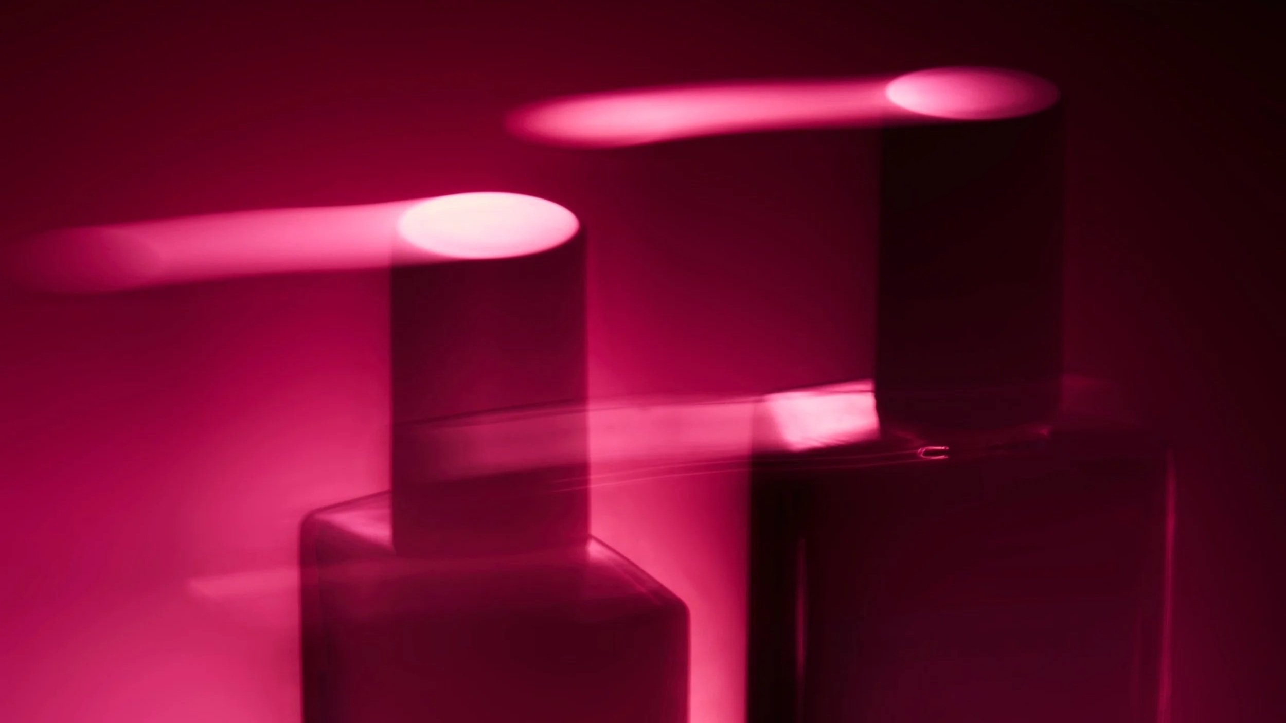 An abstract image of perfume bottles with pink light effects, creating a futuristic and artistic visual. Creative lighting