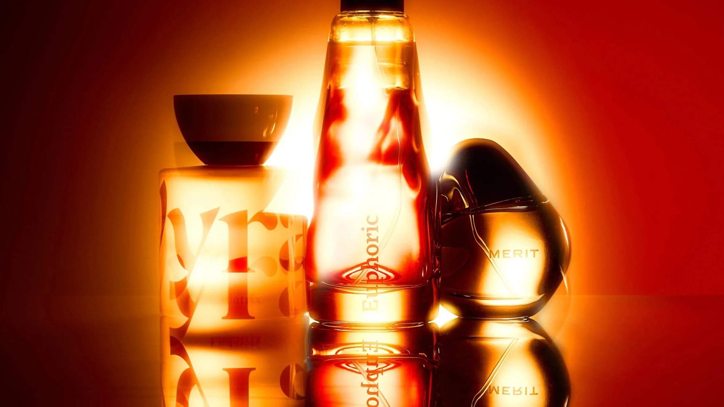 A collection of perfume bottles and a decorative container illuminated with warm orange and yellow light.