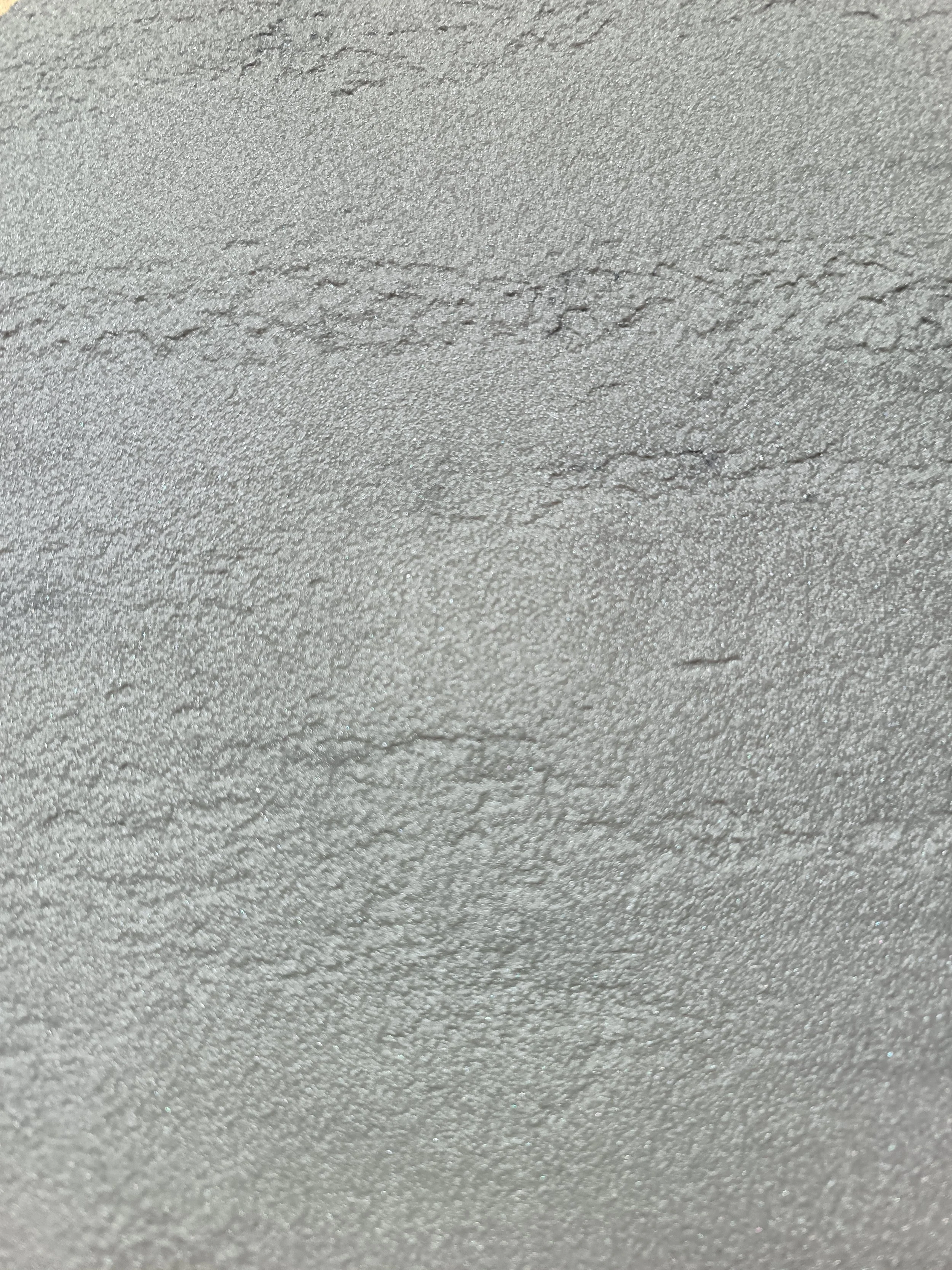 Close-up of a textured silver-colored surface with fine granular texture and subtle shading variations.