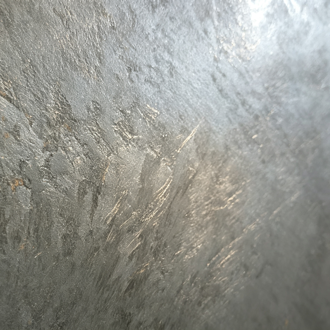 Close-up of a textured silver-gray metallic surface with scratches and irregularities.