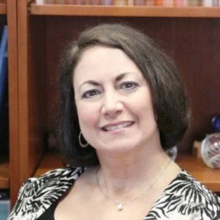 Woman smiling in front of bookshelf, black and white photo