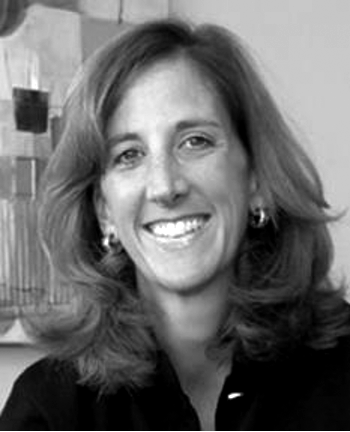 Smiling person with shoulder-length hair in a black and white photo