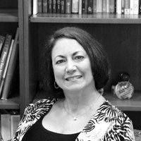 Woman smiling in front of bookshelf, black and white photo